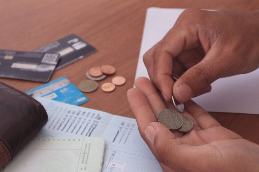 Mans hand counting coins with ATM cards and coin in the background